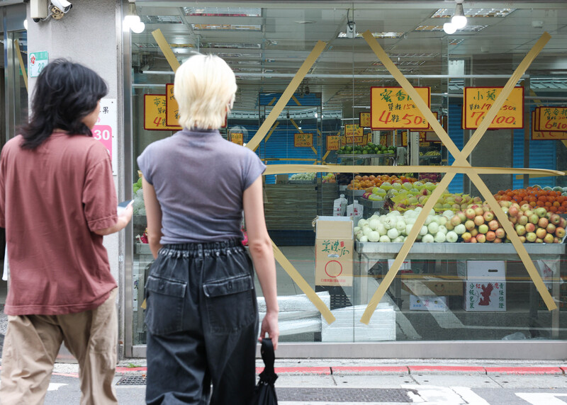 颱風丹娜絲來襲，台北市松山區店家加強防颱工作，預先在玻璃窗貼上膠帶。

