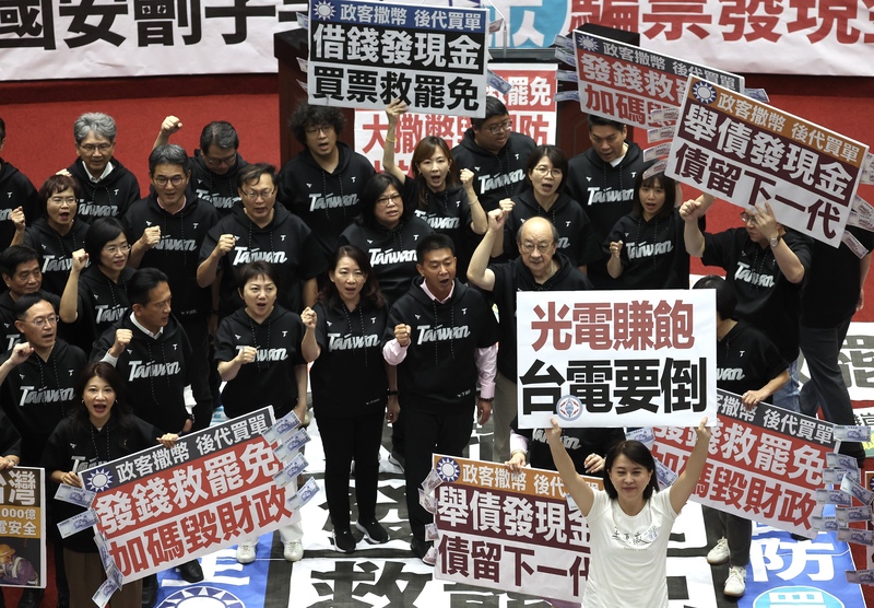 立法院日前三讀通過國民黨提出的特別條例，其中包含「普發現金」新台幣1萬元。圖為三讀後，朝野立委各自在議場內舉牌表達不同立場。