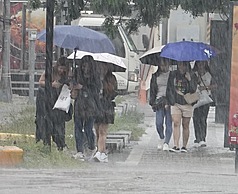 圖為高雄市區降雨，路上行人撐傘。資料照。
