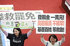 立法院會通過特別條例，在野刪除撥補台電千億預算，納全民普發現金一萬。民進黨立委吳思瑤（左）、國民黨立委王鴻薇（右）在場內各自舉牌表達立場。(中央社)
