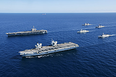 由英國「威爾斯親王號」（左前）和美國「喬治華盛頓號」（左後）航空母艦率領的打擊群，18日聯合澳洲、挪威、加拿大軍艦，在帝汶海展示「雙航艦」打擊群操演陣容，展現對印太區域的安全承諾。