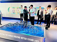 大阪府知事吉村洋文（右）26日造訪大阪世博TECH WORLD館，在正式參觀之前，由館長邱揮立(左)協助配戴智慧手環。(TECH WORLD館提供/中央社)
