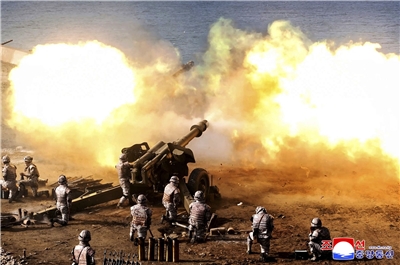 北韓官媒24日發布的照片顯示，砲兵部隊的士兵向海上發射砲彈。