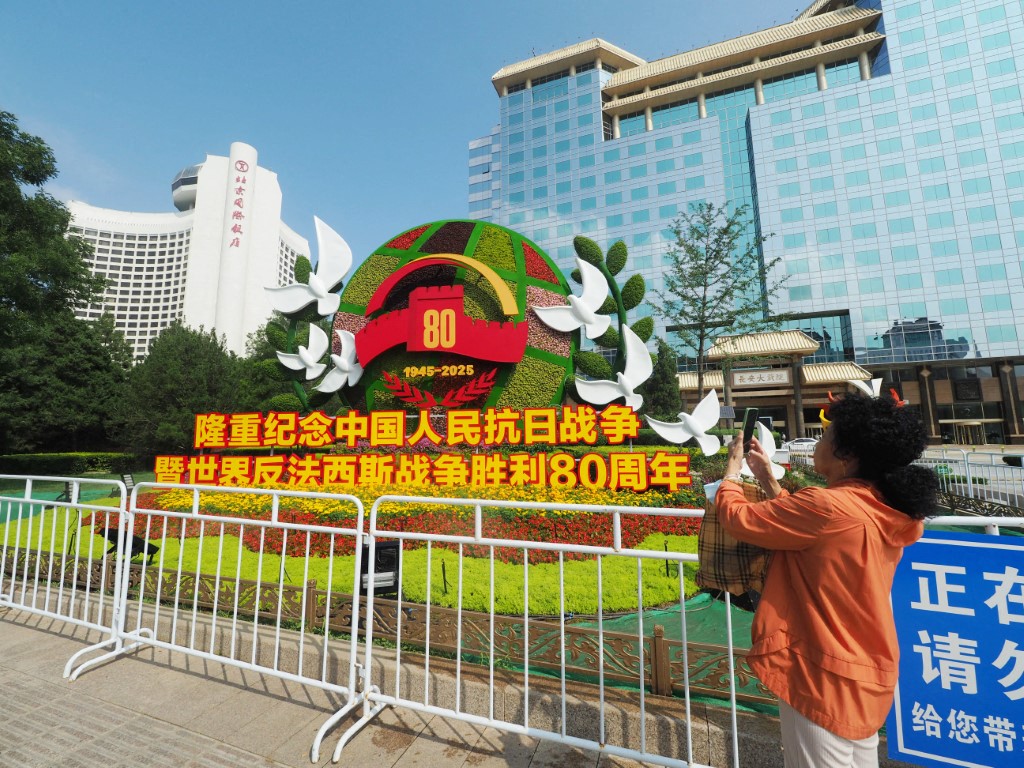 中國以「中國人民抗日戰爭暨世界反法西斯戰爭勝利80週年」的名目舉辦閱兵。圖為北京街頭設置的主題花壇。(AFP)