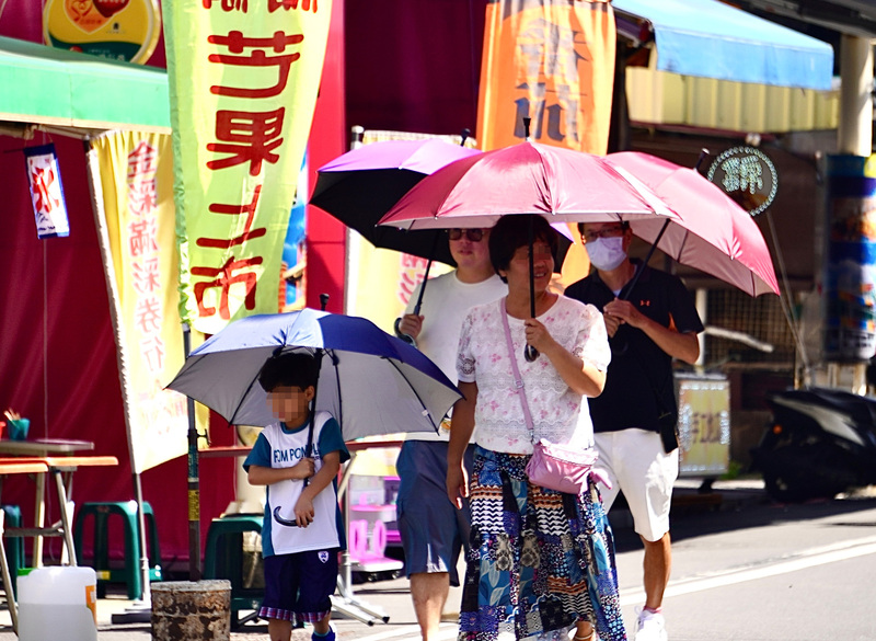 圖為赴高雄旗津老街觀光旅遊的民眾撐傘遮陽。資料照

