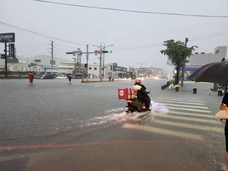 西南氣流影響，台南2日明顯降雨，永康區時雨量逾100毫米，部份區域排水不及，淹水嚴重，圖為外送員騎車冒險涉水經過積水路口。（台南市消防局提供）

