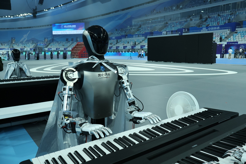 2025世界人形機器人運動會日前在中國國家速滑館「冰絲帶」舉行。圖為機器人彈鋼琴，一旁有電
風扇幫機器人降溫。(中央社)
