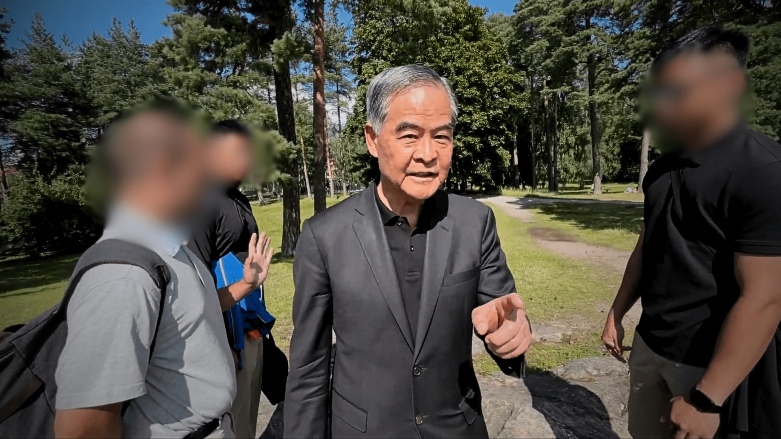 梁振英（中）與妻子唐青儀（後右）要芬蘭一處公園內的法輪功學員交代姓名、經濟背景等個人訊息。((FALUNINFO)