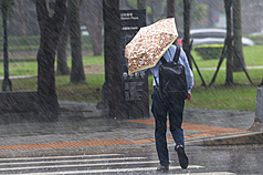 氣象專家吳德榮表示，今明兩天(3日、4日)西南季風影響，迎風面中南部連日多雨。圖為大雨期間，外出民眾撐傘前行。(中央社)
