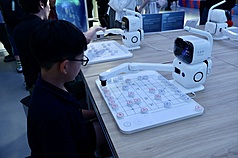 全球首個以具身智慧機器人為核心的4S店在北京亮相。圖為兒童與店內展示的下棋機器人對弈。