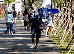 中央氣象署指出，今天(24日)各地天氣高溫炎熱，其中大台北及桃園地區有可能出現局部37度左右或以上的高溫。圖為駁二藝術特區周邊有民眾以毛巾蓋頭防曬、遮擋豔陽。