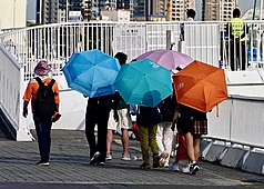 圖為高雄駁二藝術特區周邊民眾撐傘遮陽。資料照。
