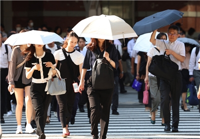 東京連日高溫，通勤族忙撐傘遮陽。