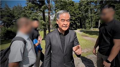 梁振英（中）與妻子唐青儀（後右）被指控要求芬蘭一處公園內的法輪功學員交代姓名、經濟背景等個資。((FALUNINFO)