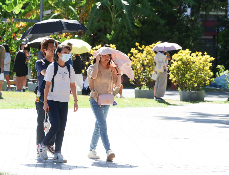 天氣炎熱高溫。圖為台北華山文創園區出遊民眾以陽傘、隨身衣物遮擋豔陽。(資料照片)

