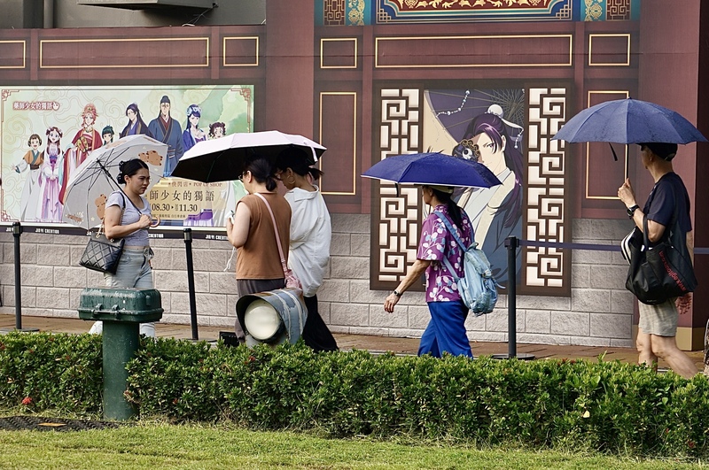 圖為高雄駁二藝術特區周邊民眾撐傘遮陽。資料照。