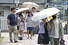 天氣連日炎熱高溫，圖為台北市南港區民眾撐傘遮陽。(資料照片)
