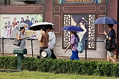 圖為高雄駁二藝術特區周邊民眾撐傘遮陽。資料照。
