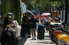 天氣炎熱高溫，民眾在台北市信義區外出，走在陰影下遮陽。(資料照片)
