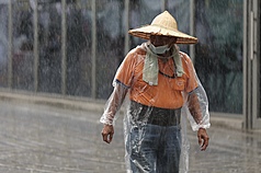樺加沙颱風警報，北部白天出現間歇性大雨。圖為台北市南港區民眾穿著雨衣戴斗笠擋雨。

