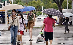 颱風樺加沙來襲，高雄民眾撐傘過馬路。