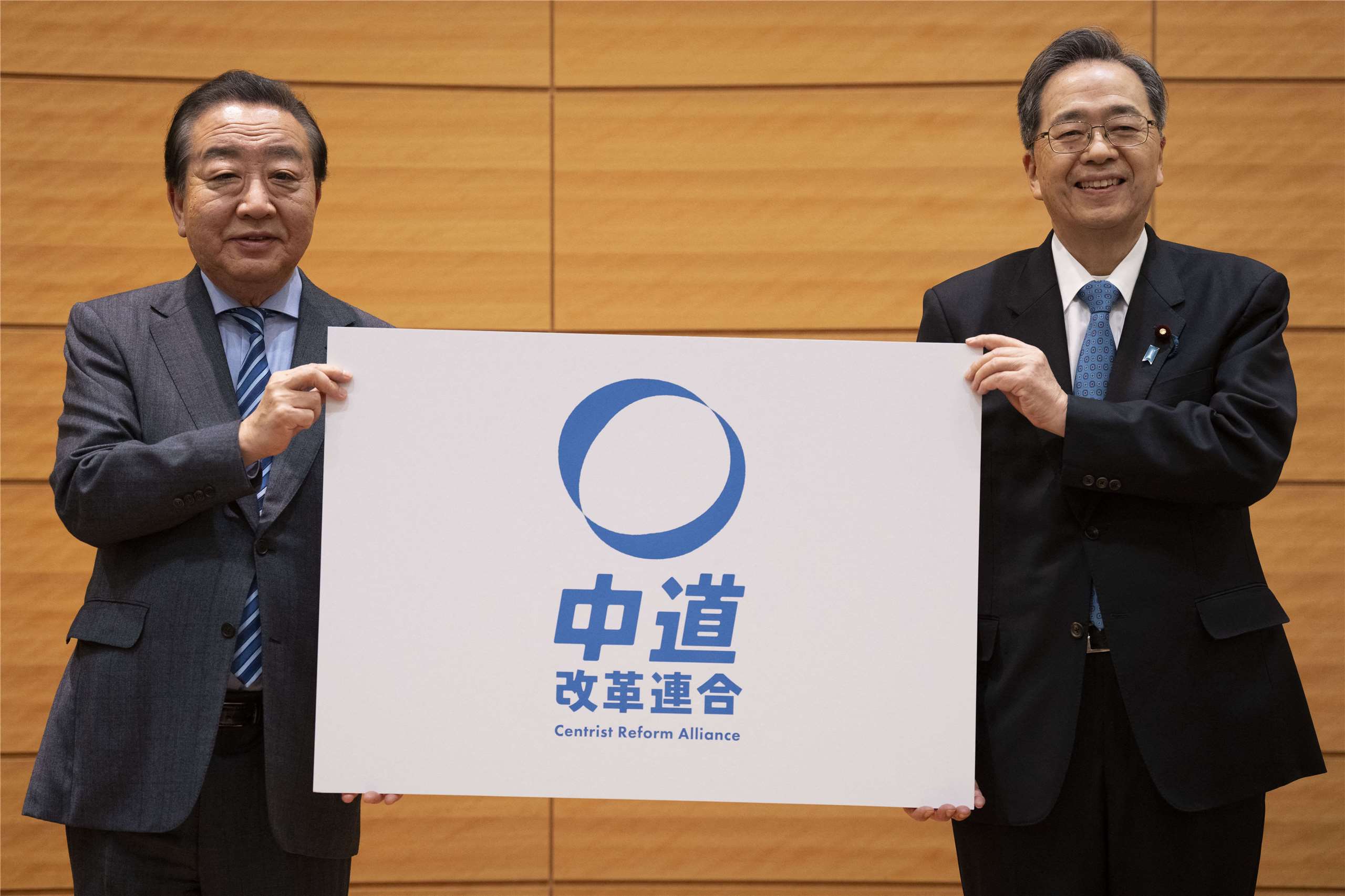 公明黨代表齊藤鐵夫(右)與立憲民主黨代表、前首相野田佳彥(左)16日一同舉起圓形淡藍色的新黨徽，宣誓新政黨「中道改革連合」正式成立。(AFP)

