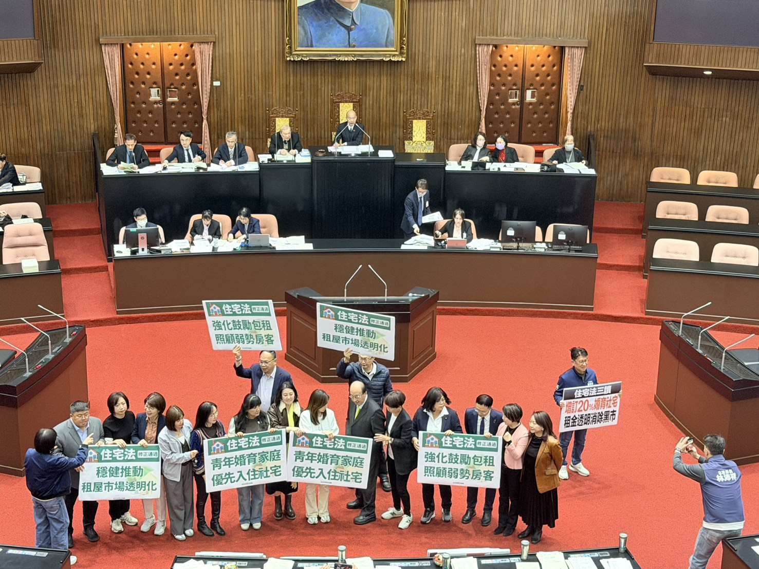 在藍、綠、白立委共同支持下，立法院會今天(30日)三讀修正通過住宅法，明定社宅應提供至少20%作為婚育宅。民進黨團在議場內高舉「青年婚育家庭、優先入住社宅」、「強化鼓勵包租、照顧 弱勢房客」、「穩定推動、租屋市場透明化」手板，力挺住宅法修法通過。(趙婉淳 攝)