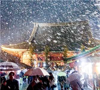 強烈冷氣團在2日為東京帶來今年首場降雪，適逢新年假期，許多民眾在細雪紛飛下前往台東區淺草寺進行新年參拜。(AFP)