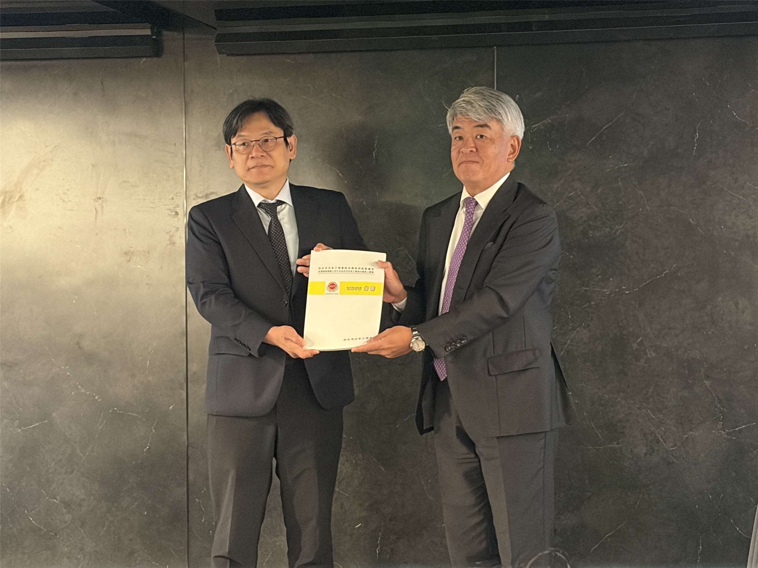 國發會主委葉俊顯(左)自台北市日本工商會理事長增田裕一(右)手中接下2026年度白皮書。(謝佳興 攝)