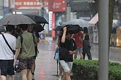 氣象署5日下午更新大雨特報，受東北季風影響及午後對流旺盛，大雨範圍擴大為北北基等13縣市。圖為民眾以包包遮擋雨勢。