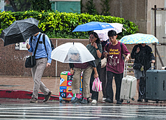 未來一周有2波東北季風，迎風面易有局部短暫雨。圖為民眾撐傘遮雨。資料照。