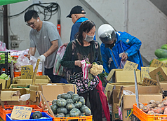 颱風薔琵造成的農業災損待查估。圖為新北市一處傳統市場攤商風雨中營業，民眾前往採買食材。