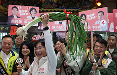 民進黨新北市長參選人蘇巧慧(前左3)29日一早前往三重果菜市場掃街拜票，並高舉蒜苗與眾人高喊「凍
蒜」口號。