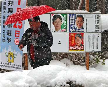 日本眾議院選舉投開票今天(8日)登場，投票將在晚間 8點(台灣時間晚間7點)結束。日本福井縣福井市民眾走過眾議院選舉候選人看板。(AP/達志影像)