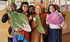 南非佛光山南華寺新春期間舉辦蔬食品嘗會，覺諦法師（前排中）與當地青年手持蔬菜造型道具合影，倡議蔬食永續與愛護生命理念。