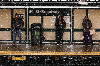 圖為紐約客在風雪中等待地鐵列車進站。