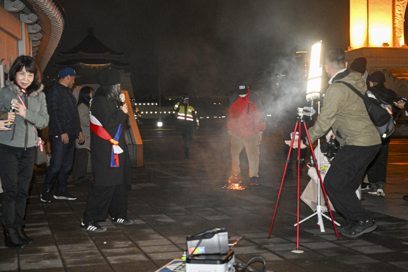 西藏抗暴67週年，在台藏人團體10日晚間在台北自由廣場舉行燭光晚會，不過現場一名男子（後右紅衣者）活動中突然扔擲鞭炮，地面一度爆出火花與煙霧，引發關注。
