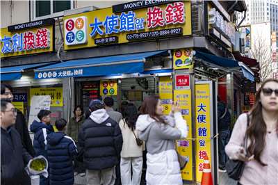 日中關係惡化後，中國遊客紛紛放棄日本轉赴韓國旅遊。圖為遊客在首爾明洞中國大使館前的貨幣兌換處，排隊兌換外幣。(AFP)