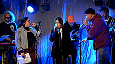 為向戰爭中的受難者致意與聲援，巴(黎)15日舉行「為了伊朗」籌款音樂會，共20位藝術家參與。伊朗流亡饒舌女歌手朱斯蒂娜（圖中著領帶者）與美國饒舌歌手麥克賴德（圖右戴帽者）合唱，以音樂表達不懼強權，呼籲人民團結。
