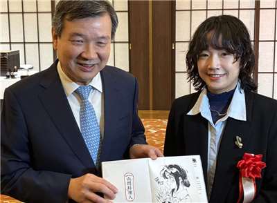 台灣漫畫家南南日(右)以作品「Mararum：山間料理人」榮獲第19屆日本國際漫畫獎優秀獎(銀獎)，並親赴東京領獎。駐日代表李逸洋(左)亦受邀出席典禮，向南南日表達祝賀。(翻攝台北駐日經濟文化代表處臉書)