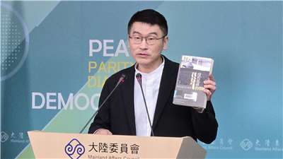 陸委會副主委梁文傑在記者會上，拿出八旗文化總編輯富察出版的書。(陳國維 攝)