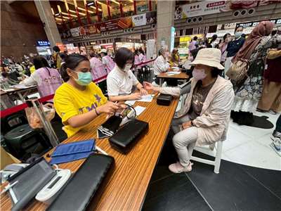 北醫新南向培育專班學生在北車協助移工量血壓。(臺北醫學大學提供)