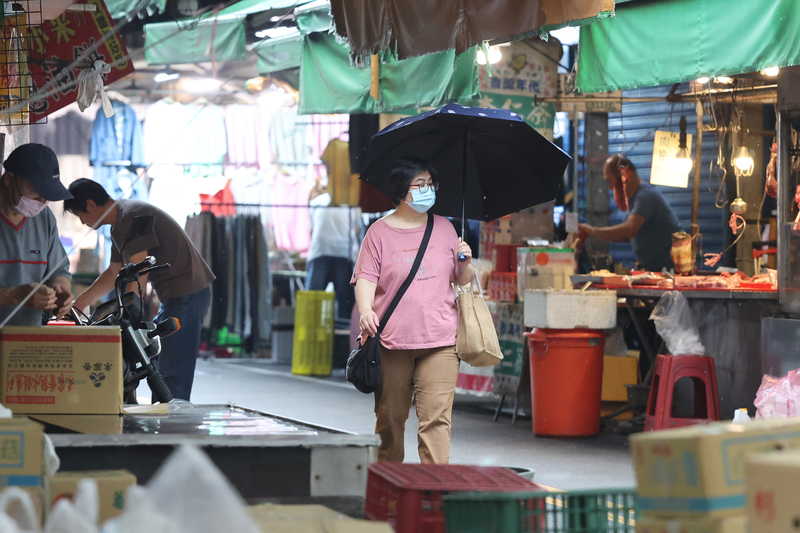 新北市板橋區18日下午出現陣雨情形，民眾撐傘外出。