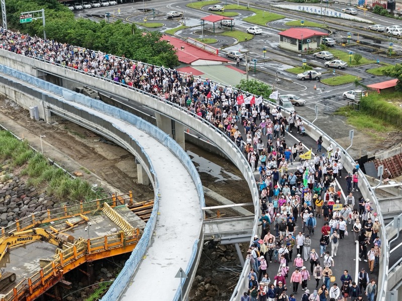 新北市府民政局25日舉辦淡江大橋通車前健行暖身活動，吸引綿延的人龍上橋，飽覽淡水河口景色。圖為空拍照片，參加健行人潮相當壯觀。