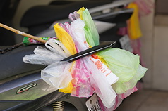 中東戰事導致原物料供應大亂，傳出塑膠包材短缺現象。有民眾2日將用過的塑膠袋集中塞在機車後扶手上，回收再利用。資料照片。 
