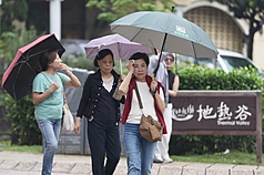 中央氣象署發布豪雨特報，受到鋒面影響易有短延時強降雨，遊客4日在台北市北投區撐傘遮雨。