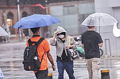 圖為台北西門町商圈傍晚出現雨勢，未備雨具民眾拉緊外套帽沿擋雨。