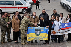 台灣民間共同籌募的68輛救護及救災車輛23日運抵烏克蘭，台灣社區關懷協會秘書長林偉聯（前排右）在援贈交車儀式與烏方代表握手。
（利維夫市政府提供）
