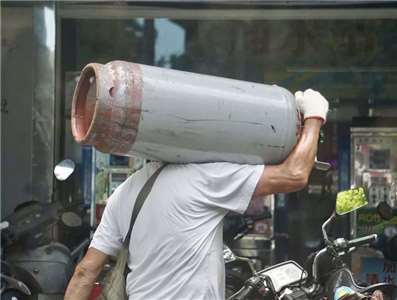 圖為瓦斯業者將桶裝瓦斯扛在肩上搬運。資料照。