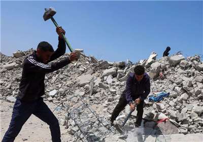 2026年4月19日，巴勒斯坦工人在加薩走廊南部汗尤尼斯清理瓦礫時，正敲碎混凝土。(路透社/達志影像)